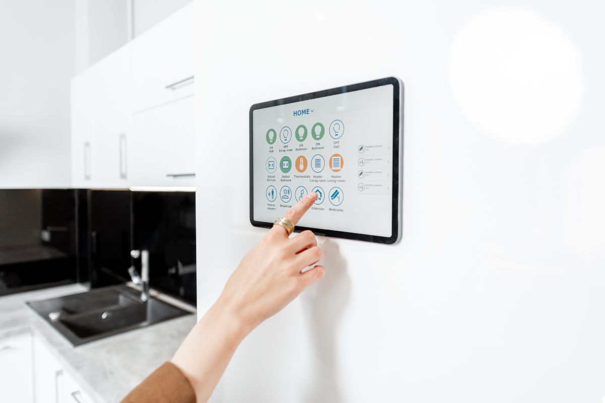 A person interacting with a tablet while standing against a white wall.